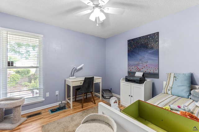 bedroom featuring wood finished floors, a textured ceiling, baseboards, and a ceiling fan