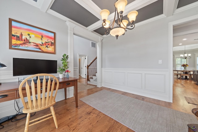 office area featuring a chandelier, crown molding, wood finished floors, a wainscoted wall, and a decorative wall
