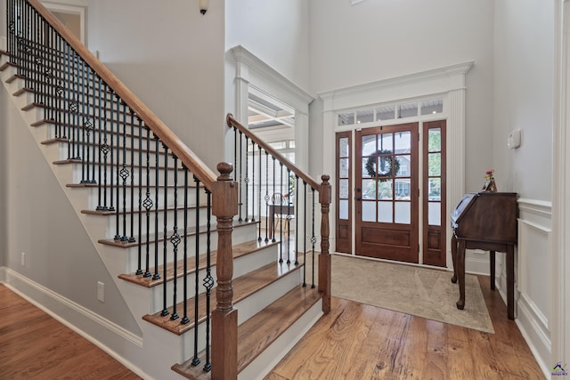entrance foyer with wood finished floors, a towering ceiling, and stairs