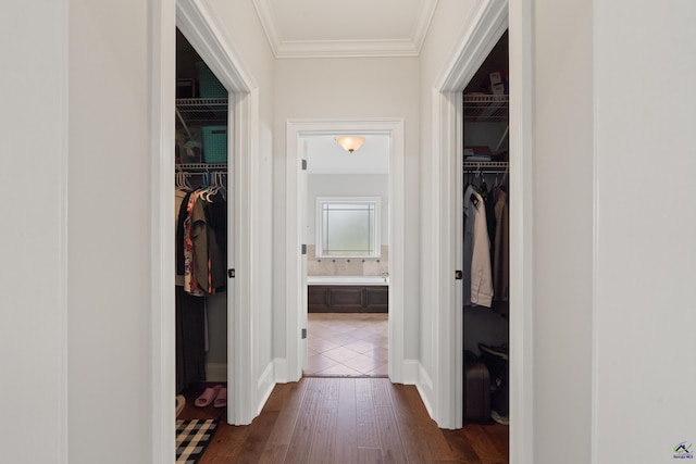 hallway featuring ornamental molding, dark wood-style flooring, and baseboards
