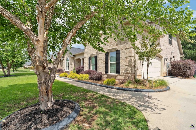 view of front of home featuring concrete driveway, a front lawn, brick siding, and an attached garage