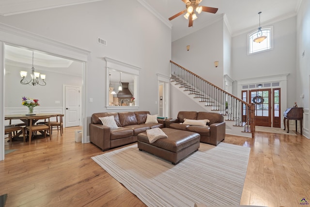 living area featuring stairway, light wood-type flooring, a high ceiling, healthy amount of natural light, and a ceiling fan