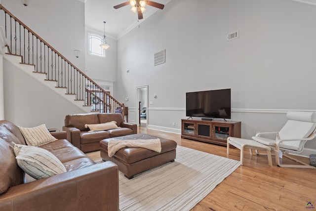 living room featuring high vaulted ceiling, stairs, ceiling fan, wood finished floors, and crown molding