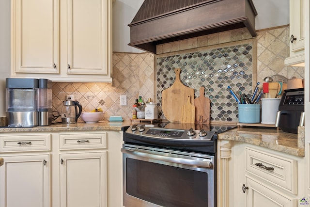 kitchen with stainless steel range with electric cooktop, custom exhaust hood, and cream cabinetry