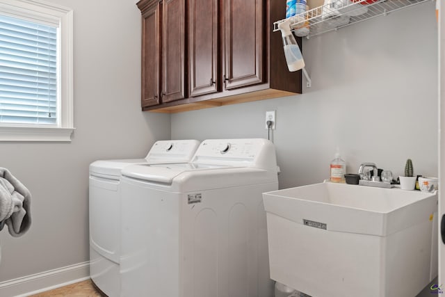 laundry area featuring separate washer and dryer, cabinet space, and baseboards