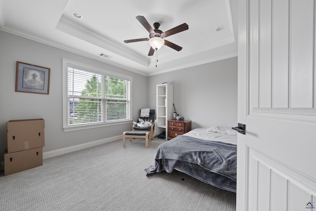 bedroom with a tray ceiling, crown molding, carpet, baseboards, and a ceiling fan