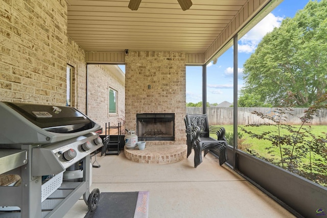 sunroom with an outdoor brick fireplace and ceiling fan