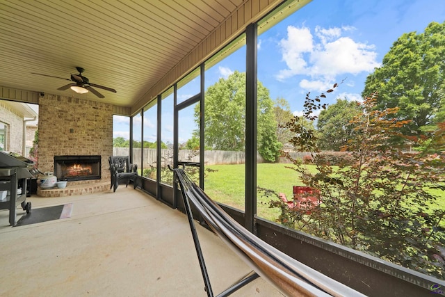 sunroom / solarium featuring a fireplace and a ceiling fan