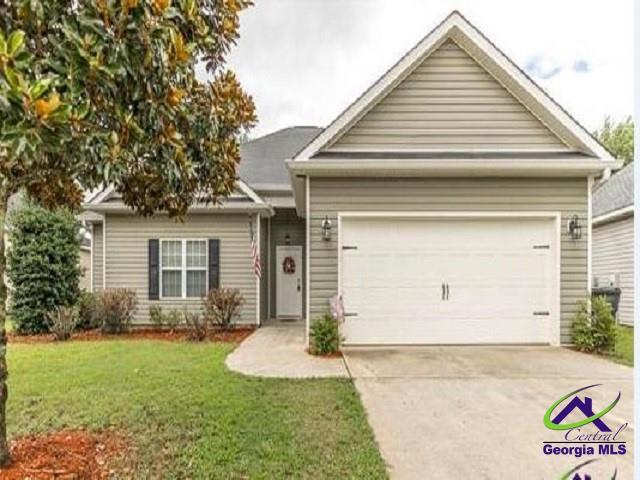 view of front of property featuring concrete driveway, an attached garage, and a front yard