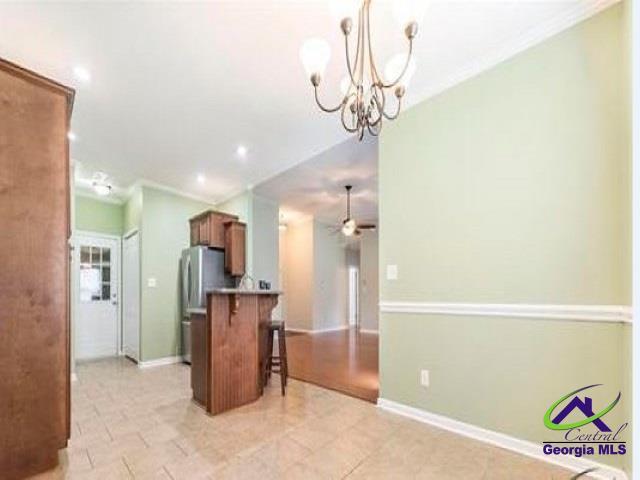 kitchen featuring a breakfast bar, brown cabinets, ornamental molding, ceiling fan, and baseboards