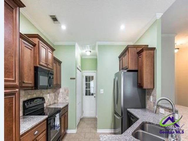 kitchen with black appliances, a sink, crown molding, backsplash, and light stone counters