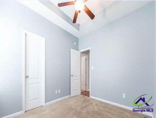 unfurnished bedroom with lofted ceiling, light carpet, and baseboards