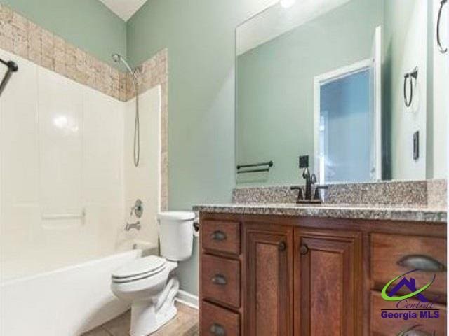 bathroom featuring toilet, bathing tub / shower combination, and vanity