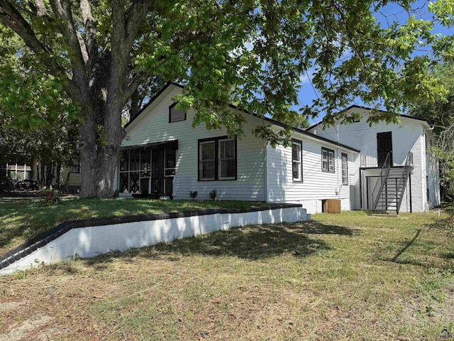 back of house with stairs, a yard, and a sunroom