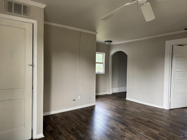spare room featuring arched walkways, a ceiling fan, ornamental molding, dark wood-type flooring, and baseboards