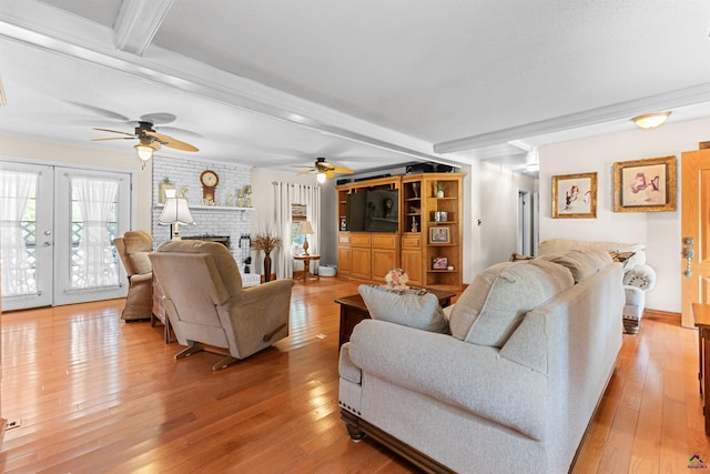 living area with ceiling fan, light wood-type flooring, beamed ceiling, french doors, and a fireplace