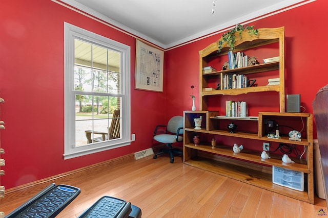 living area with ornamental molding, wood finished floors, and baseboards