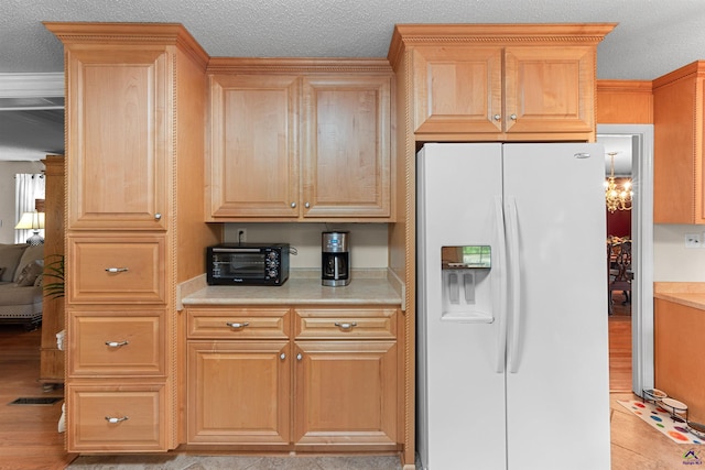 kitchen with white refrigerator with ice dispenser, light brown cabinets, light countertops, a textured ceiling, and light wood finished floors