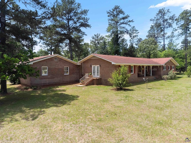 view of front facade featuring french doors, brick siding, and a front yard