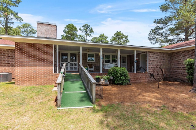 property entrance with central AC, a chimney, a yard, and brick siding