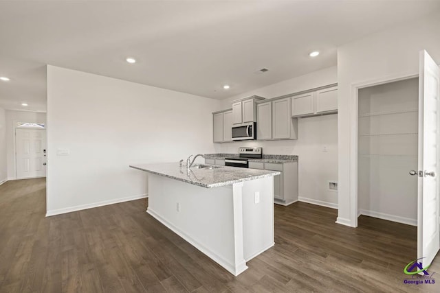 kitchen with gray cabinets, appliances with stainless steel finishes, a kitchen island with sink, dark wood-style flooring, and recessed lighting