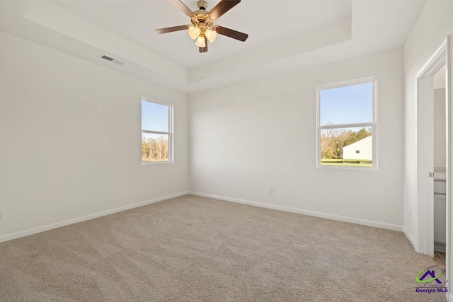 unfurnished bedroom with carpet flooring, baseboards, and a tray ceiling