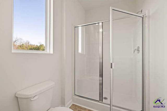 full bathroom with a shower stall, toilet, and baseboards
