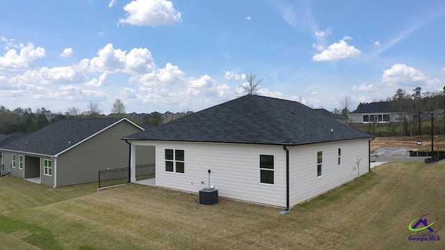 back of house with a yard and roof with shingles