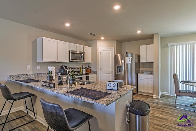 1707 Hannah Ct, Macon, GA 31217 - kitchen featuring appliances with stainless steel finishes, a peninsula, dark wood finished floors, a sink, and light stone counters