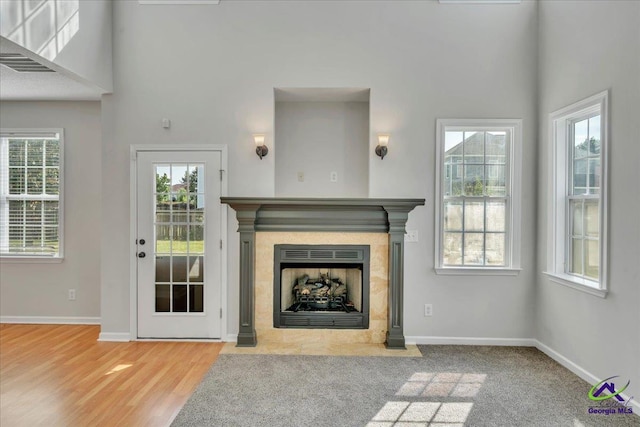 212 Raleigh Dr, Warner Robins, GA 31088 - unfurnished living room featuring baseboards, a fireplace with flush hearth, healthy amount of natural light, a towering ceiling, and wood finished floors