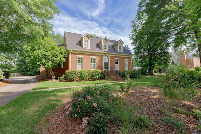 view of front of house featuring brick siding, a front yard, and driveway