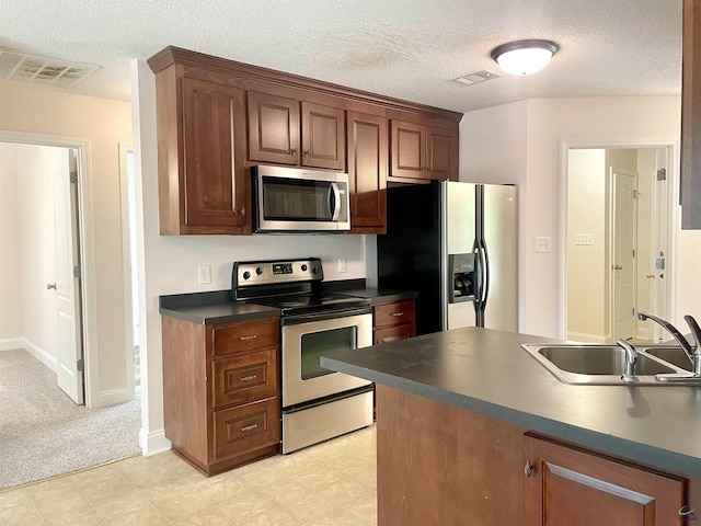 1187 Camden Ct, Warner Robins, GA 31088 - kitchen with appliances with stainless steel finishes, a sink, dark countertops, a textured ceiling, and baseboards