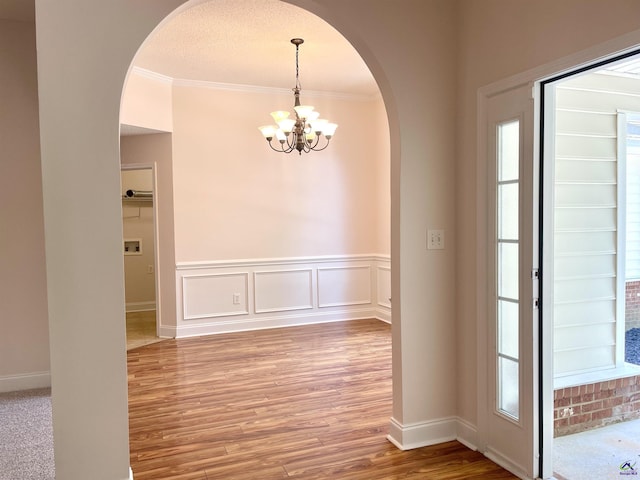 1187 Camden Ct, Warner Robins, GA 31088 - entryway with arched walkways, a chandelier, crown molding, wood finished floors, and a wainscoted wall