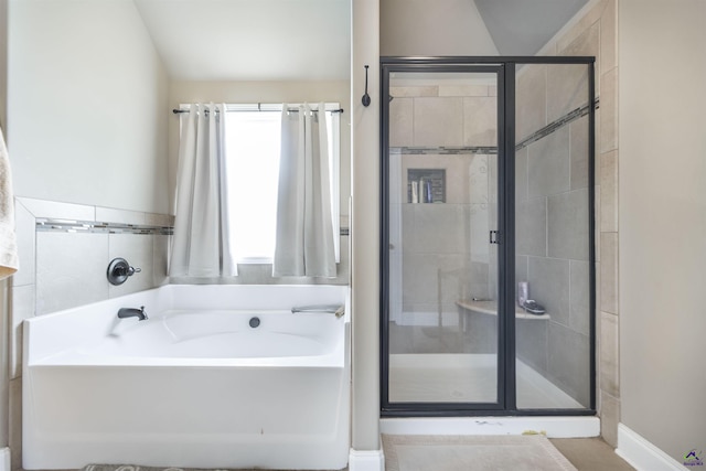 bathroom with a shower stall, a garden tub, and lofted ceiling