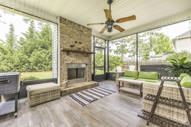 sunroom featuring a ceiling fan and an outdoor living space with a fireplace
