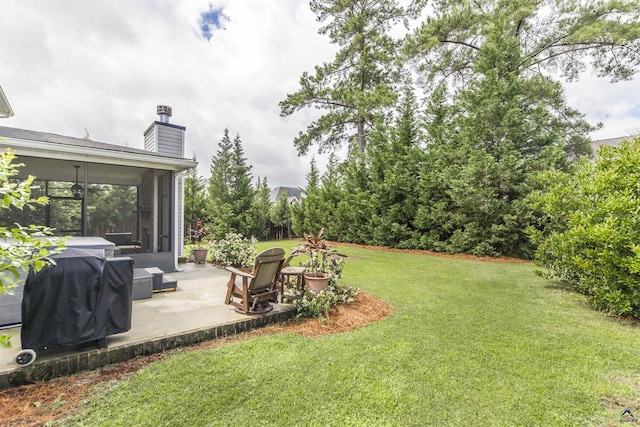 view of grassy yard with a patio area and a sunroom