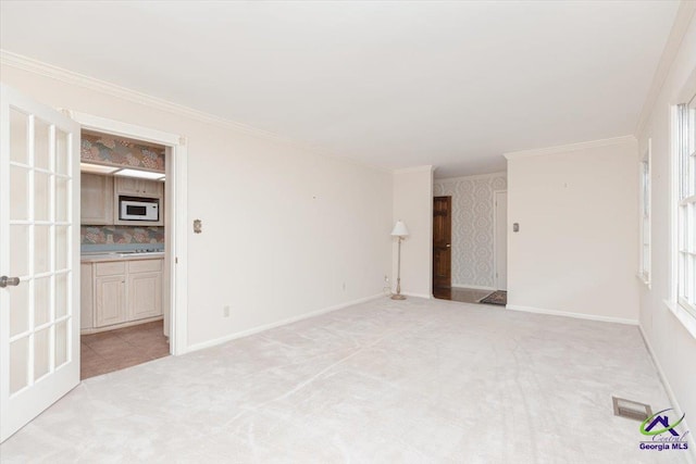 unfurnished living room featuring light carpet, ornamental molding, and baseboards