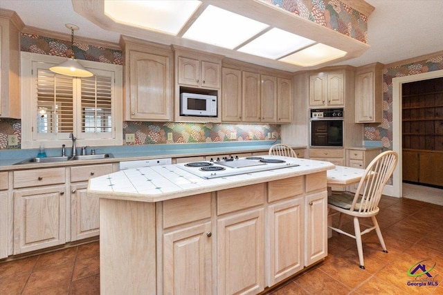 kitchen with white appliances, a sink, wallpapered walls, a kitchen island, and pendant lighting