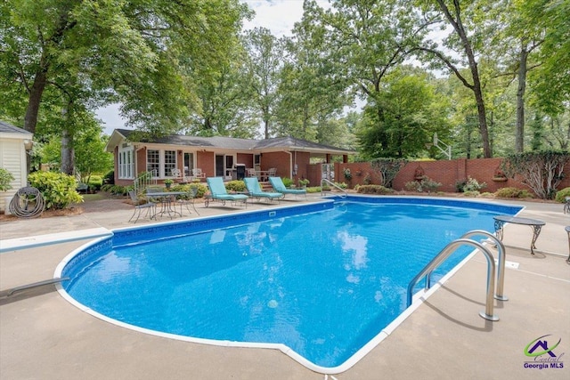 view of swimming pool featuring fence and a patio area