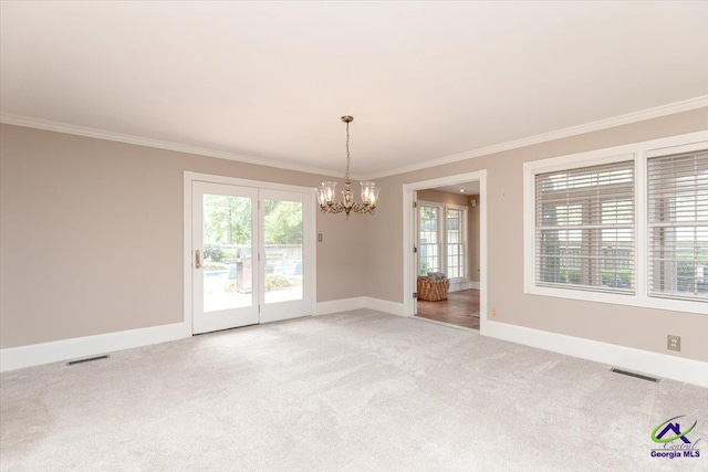 spare room featuring a chandelier, ornamental molding, light carpet, and baseboards