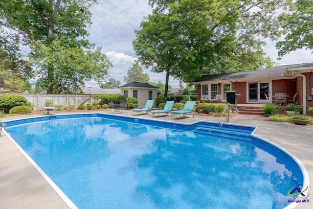 view of swimming pool with a patio area, fence, an outdoor structure, a diving board, and grilling area