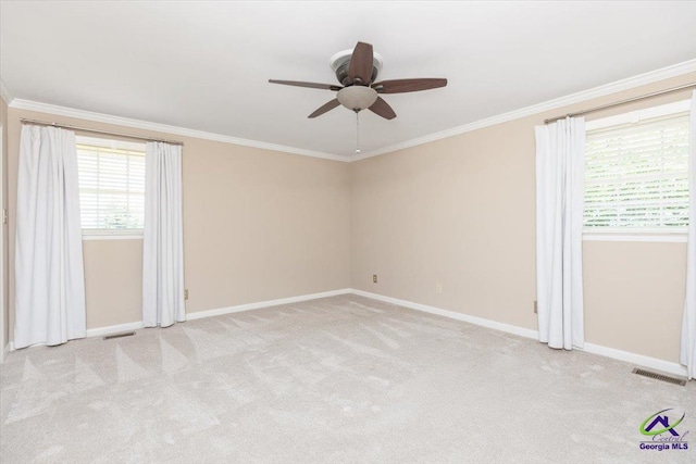 unfurnished room with ornamental molding, healthy amount of natural light, baseboards, a ceiling fan, and light colored carpet