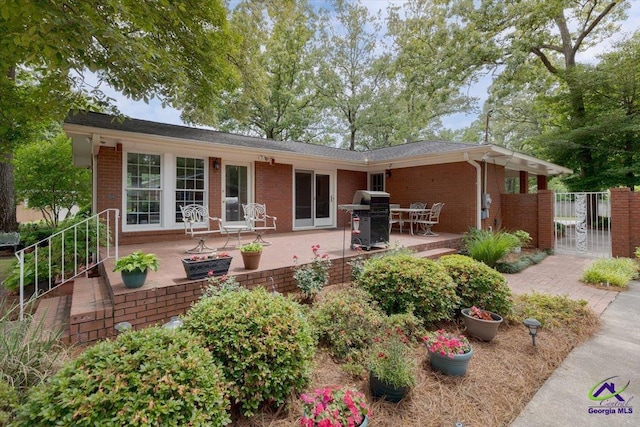 rear view of house with brick siding, a patio, and a gate