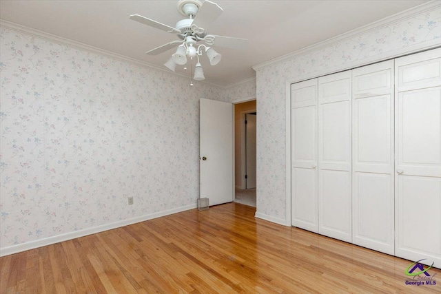 unfurnished bedroom featuring light wood-style floors, crown molding, a ceiling fan, baseboards, and wallpapered walls