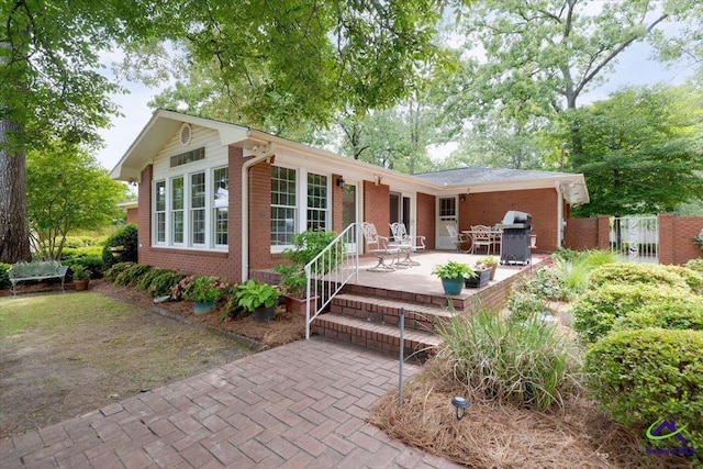 rear view of house with brick siding, a patio area, and fence