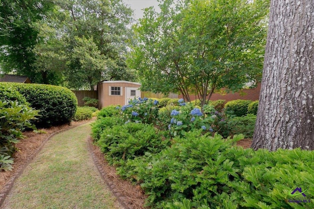 view of yard featuring a storage shed, an outdoor structure, and fence