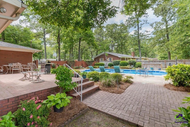 view of pool with a patio, view of wooded area, and a fenced backyard