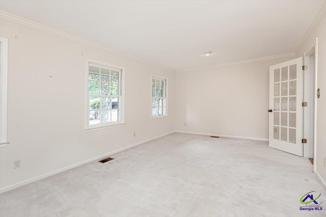 spare room featuring crown molding, baseboards, and light carpet