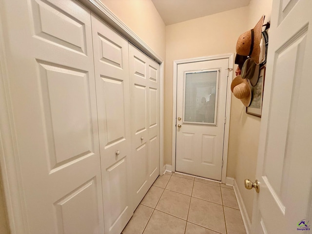 doorway to outside with light tile patterned flooring and baseboards