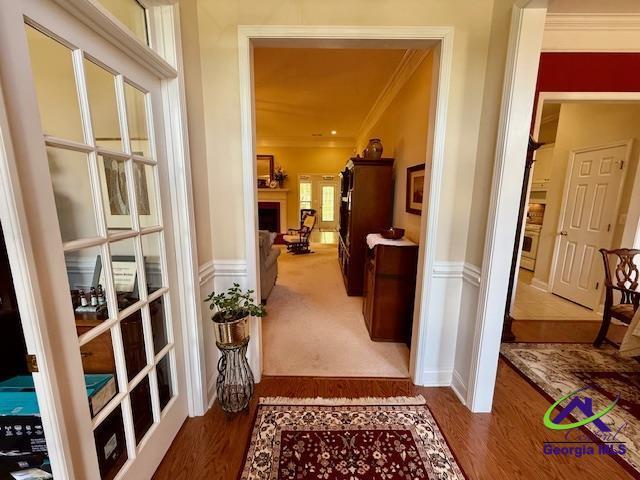 corridor featuring crown molding, wood finished floors, and french doors